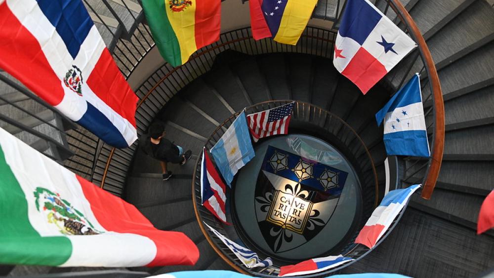 Student walking down stairs in Dominican University's Rebecca Crown Library. The stairway is decorated with flags from Latin American countries.